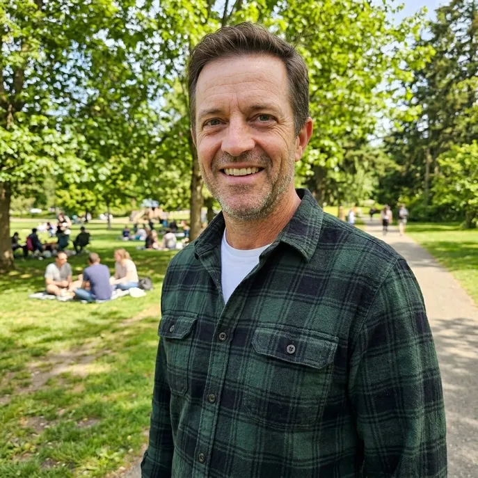 Man smiling in a green park on a sunny day